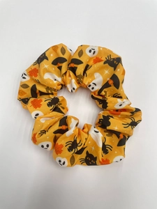 Close-up of orange Halloween scrunchie with cats, ghosts, and witch hats prints