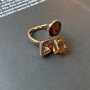 Silver open ring with geometric amber, grey, and champagne zircon stones on a dark base