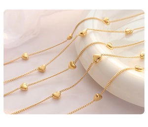 Détail de perles en acier titane doré avec plusieurs petits breloques en forme de cœur