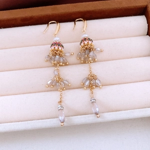 Close-up of ethnic style beaded tassel earrings with gray crystal drops on velvet display