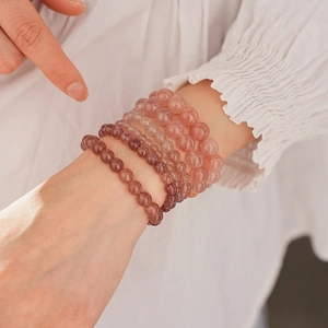 Detail of stacked strawberry quartz bracelets with natural red phantom crystal beads