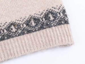Close-up of cream knit fabric with grey geometric jacquard and ribbed hem detail