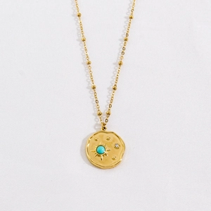Detail of gold coin necklace with turquoise stone and sparkling zircon on satellite chain