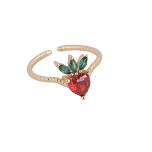 Gold cherry strawberry ring with red heart zircon and green leaf on white background