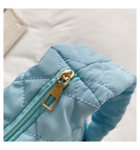 Macro shot of light blue quilted fabric bag featuring a premium gold zipper detail