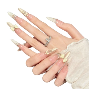 Uñas postizas stiletto nude rosa con lazos blancos 3D, perlas y brillantes pedrería