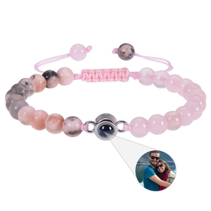 Detail of adjustable rose quartz bracelet with custom image projection charm and woven rope