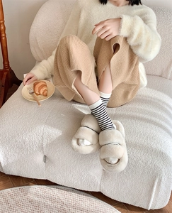 Cozy lifestyle shot of black and white striped wool socks with plush slippers and croissant