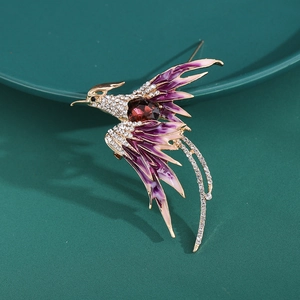 Close-up of golden phoenix brooch with purple enamel feathers and red gemstone inlay