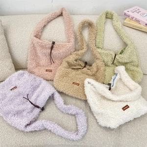 Detail view of colorful lamb wool tote bags in pink, khaki, and purple on a soft sofa