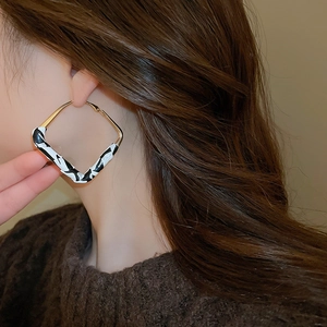 Close-up of geometric gold hoop earring with black and white leopard pattern on a model