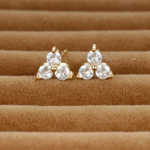 Macro view of gold clover stud earrings with sparkling round cubic zirconia stones
