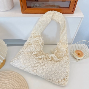 Detailed macro view of white lace tote bag with daisy embroidery and ruffle trim details