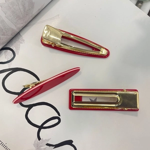 Detailed view of red resin hair clips with gold alloy back and handmade lettering