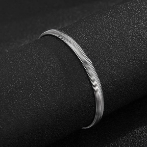 Macro shot of silver flat snake chain texture wrapped on a black cylindrical stand