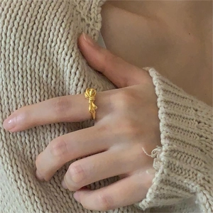 Macro view of gold bow knot ring on finger with cozy beige knit background