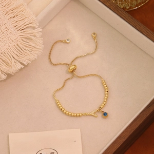 Dettaglio del bracciale regolabile in oro con occhio del male e ciondoli in cristallo