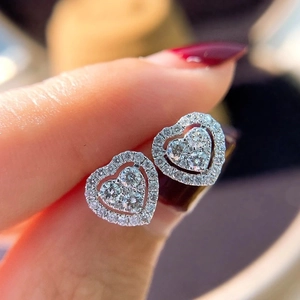 Close-up of heart-shaped silver earrings with sparkling stones on a female model
