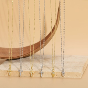 Detail of cross and teardrop pendants in 14K gold plating with shimmering cubic zirconia