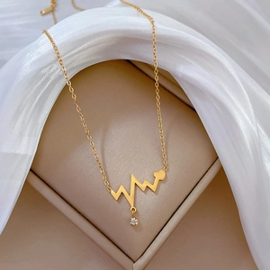 Detail of gold titanium steel heartbeat necklace with crystal heart pendant on silk