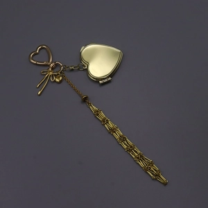 Detail of golden heart-shaped locket keychain with long tassel and bow accent