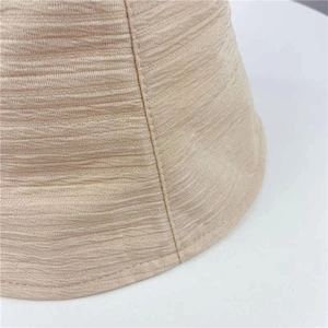 Détail macro du tissu plissé beige et coutures fines sur un chapeau bob d'été
