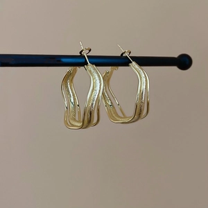 Close-up of gold irregular geometric hoop earrings with matte textured surface