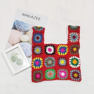 Detailed macro view of bohemian handmade granny square crochet tote bag with red floral pattern