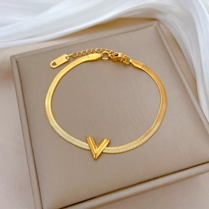 Detailed close-up of golden V-shaped pendant on snake chain with S.STEEL engraving