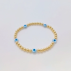 Elastic beaded bracelet with 18K gold plated copper beads and blue shell evil eye charms
