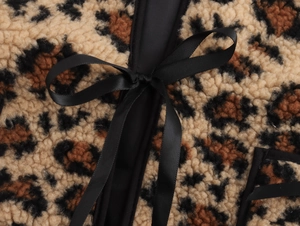 Close-up of leopard print fleece texture with a decorative black satin ribbon bow