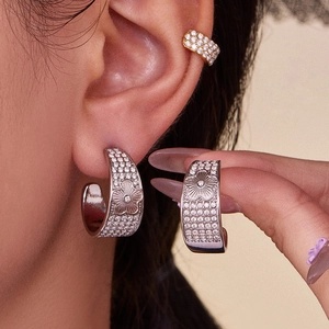 Polished stainless steel hoop earrings with zircon flower design on model