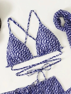 Detailed flat lay of blue wave pattern bikini set with matching shawl and ties