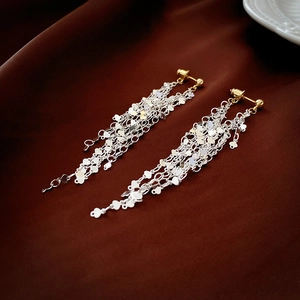 Close-up of long tassel earrings with silver sequin chains on brown silk fabric