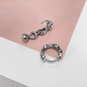 Detailed view of silver twist infinity hoop earrings with clasp mechanism on pink backdrop