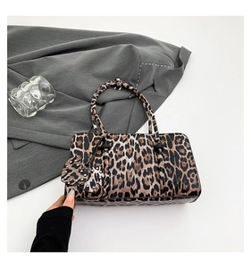 Detail of leopard print handbag with heart charm and metallic rivets on faux leather