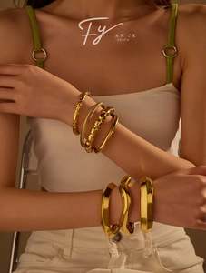 Close-up of stacked gold stainless steel bracelets with hammered and twisted textures