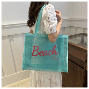 Detail of teal mesh tote bag with pink Beach Vibes text on a casual shoulder strap
