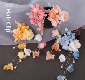 Detailed close-up of handmade floral hair clips with golden tassels and pearls in Hanfu style