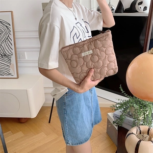 Detail of khaki quilted floral cosmetic bag with textured 3D flower pattern and zipper
