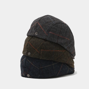 Detailed view of three herringbone newsboy caps in blue, green and grey textured wool