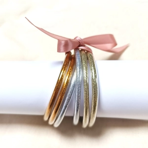 Dettaglio di cinque bracciali in resina glitterata con un fiocco in raso rosa