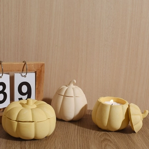 Detailed view of pumpkin-shaped ceramic storage jars and candle holders for Halloween decor