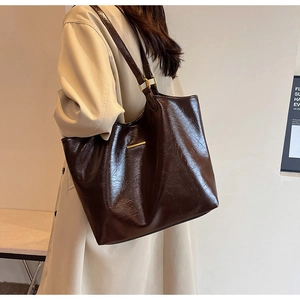 Dettaglio laterale di borsa tote in morbida pelle cerata con fibbia in metallo