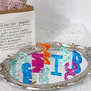 Detailed view of translucent glitter resin alphabet charms on a vintage mirror tray