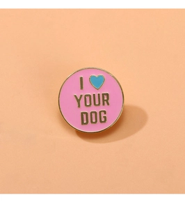 Macro detail of round pink enamel pin featuring golden I Love Your Dog text engraving