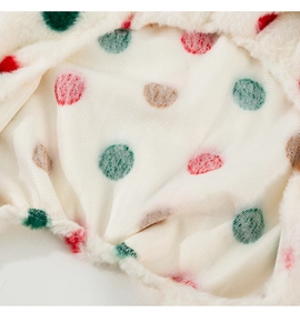Close-up of soft plush pet winter coat lining with colorful polka dots and warm faux fur texture