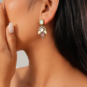 Close-up of golden vintage stud earrings with colorful gemstones and white diamonds