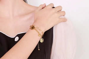 Detail of gold double-layer bracelet with hollow star-moon pendant and beads on wrist