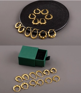 Close-up of assorted 18K gold plated hoop earrings displayed in a dark green jewelry box